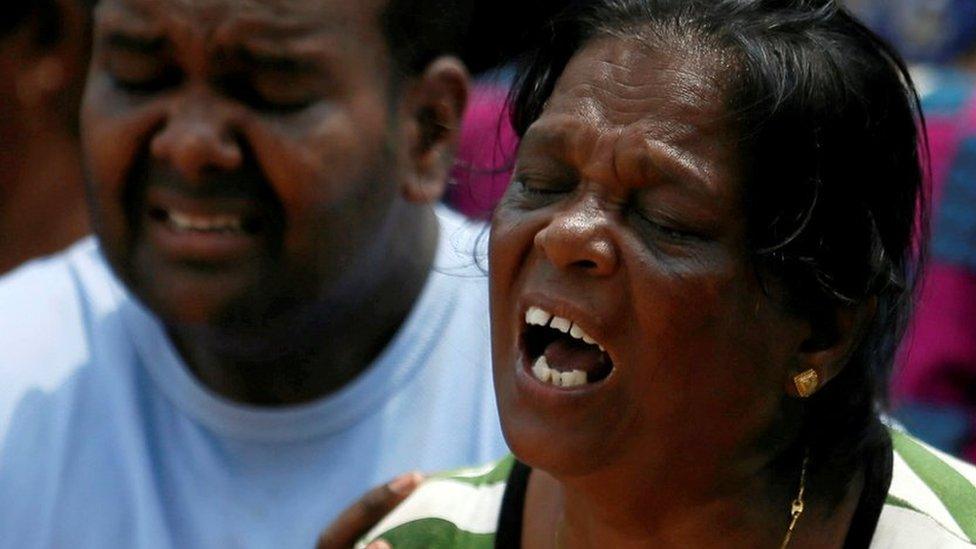 Family members of victims react during a rescue mission after a garbage dump collapsed and buried dozens of houses in Colombo