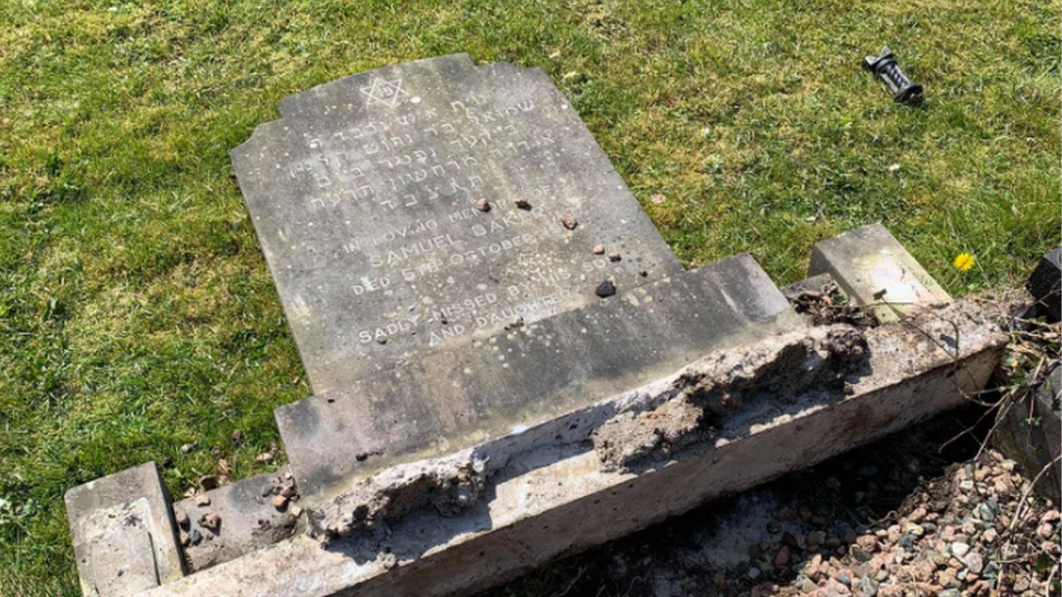 An image showing one of the gravestones laid down flat, with a star of David visible above Hebrew lettering