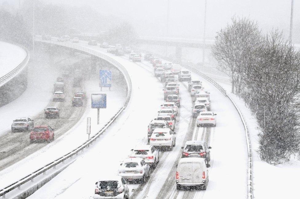 Vehicles drive through snow on the M8 in Glasgow