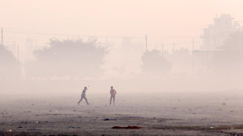 Children playing cricket in smog