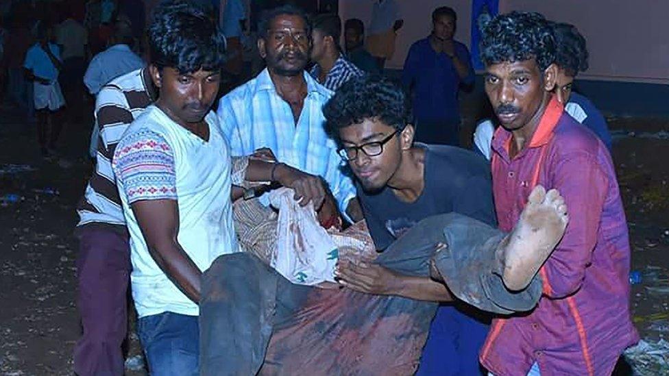 Indian bystanders carry an injured man after an explosion and fire at The Puttingal Devi Temple (Photo: AFP)