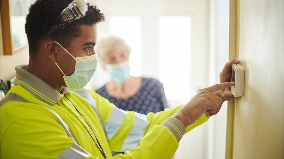 Engineer presses thermostat in hallway of home