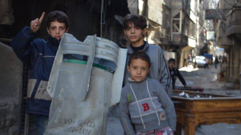 Children pose for a photograph next to an unexploded bomb