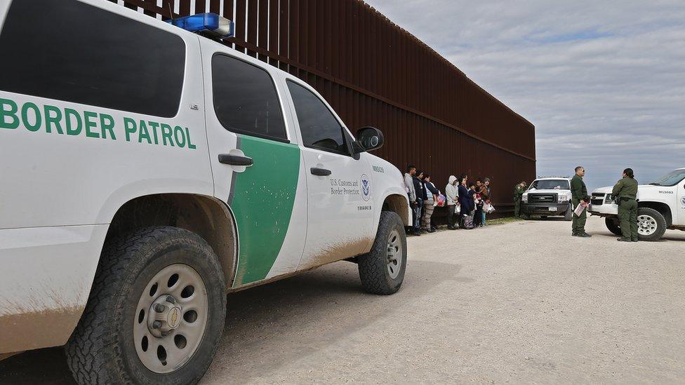 Families that crossed the border to enter the US illegally turn themselves in to US Border Patrol agents next to a fence along the Rio Grande River near McAllen, Texas, 23 January 2019