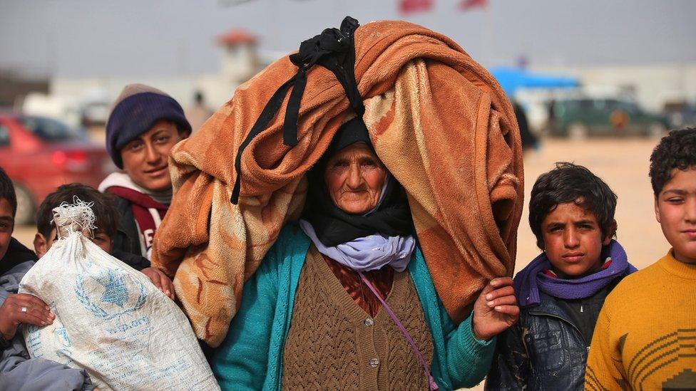 Syrians, some carrying belongings, head towards the Bab al-Salam border crossing with Turkey, in Syria, Saturday, Feb. 6, 2016