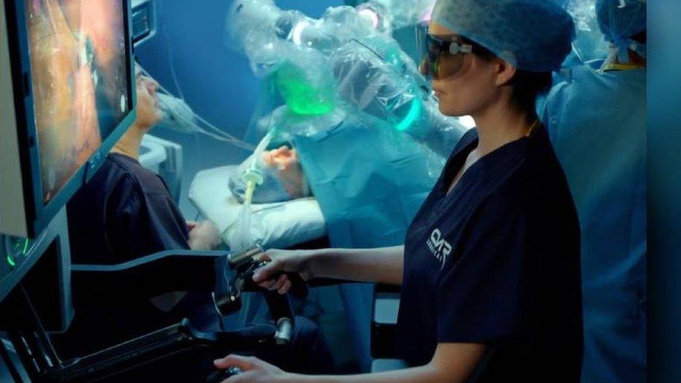 In this demonstration, a consultant works the controls while the robotic arms operate inside the patient behind. (Note this is a demo picture and the "patient" is a dummy)