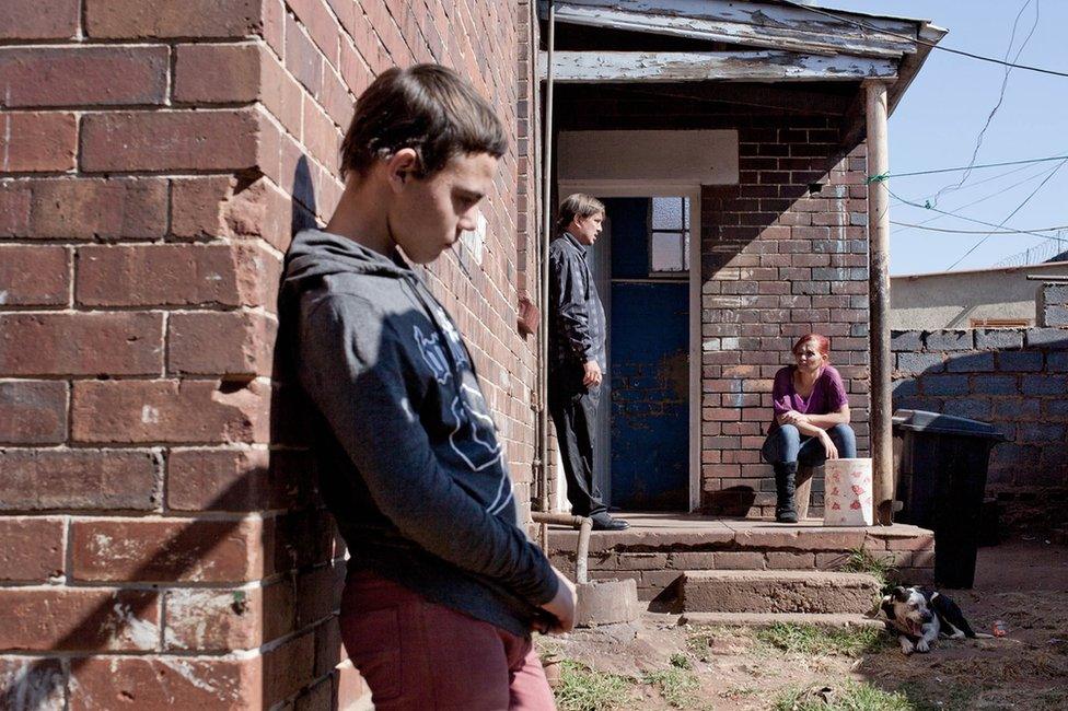 A family waits outside their house