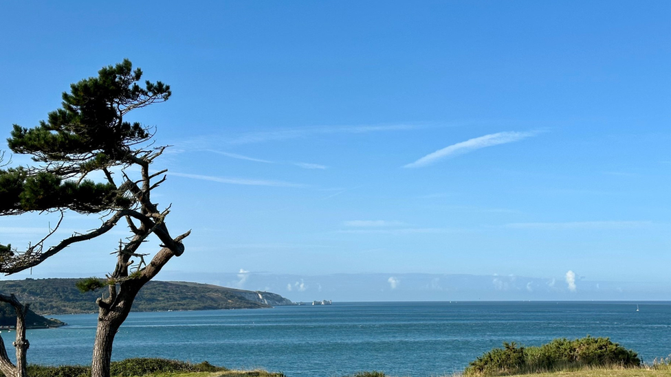 Blue skies above a calm sea, looking out in the horizon to some land.