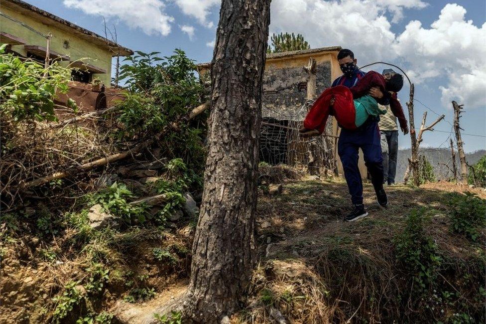 Pramila Devi, 36, who is suffering from the coronavirus disease (COVID-19), is carried by her nephew Rajesh Kumar, as he takes her to a local government dispensary, in Kaljikhal, in the northern state of Uttarakhand, India, May 23, 2021