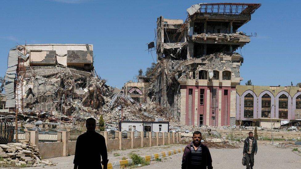 People walk past destroyed University of Mosul buildings (11 July 2017)