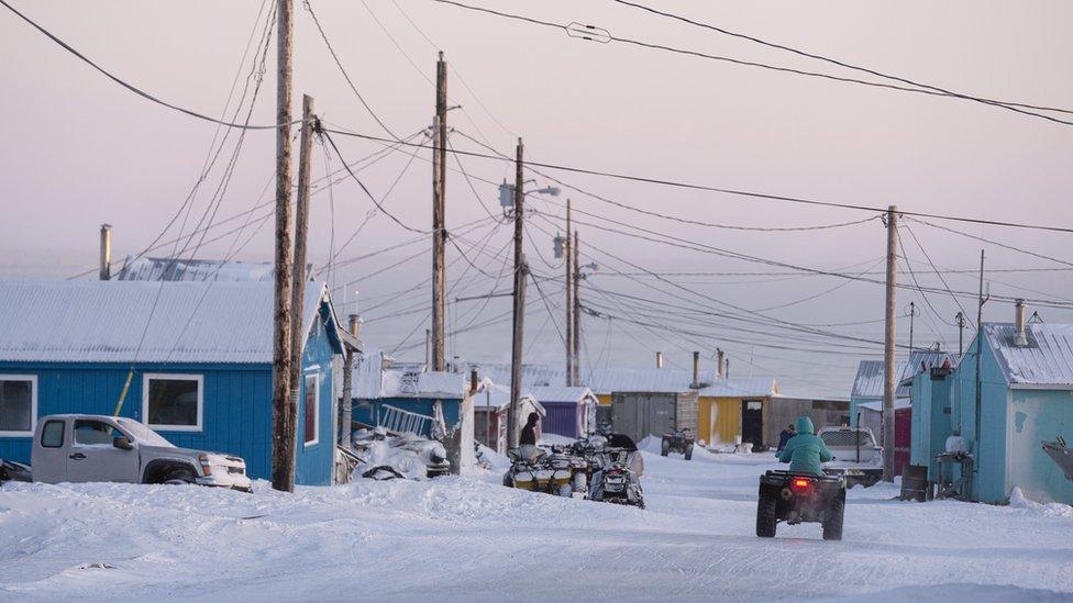 A resident riding a snowmobile in Toksook Bay