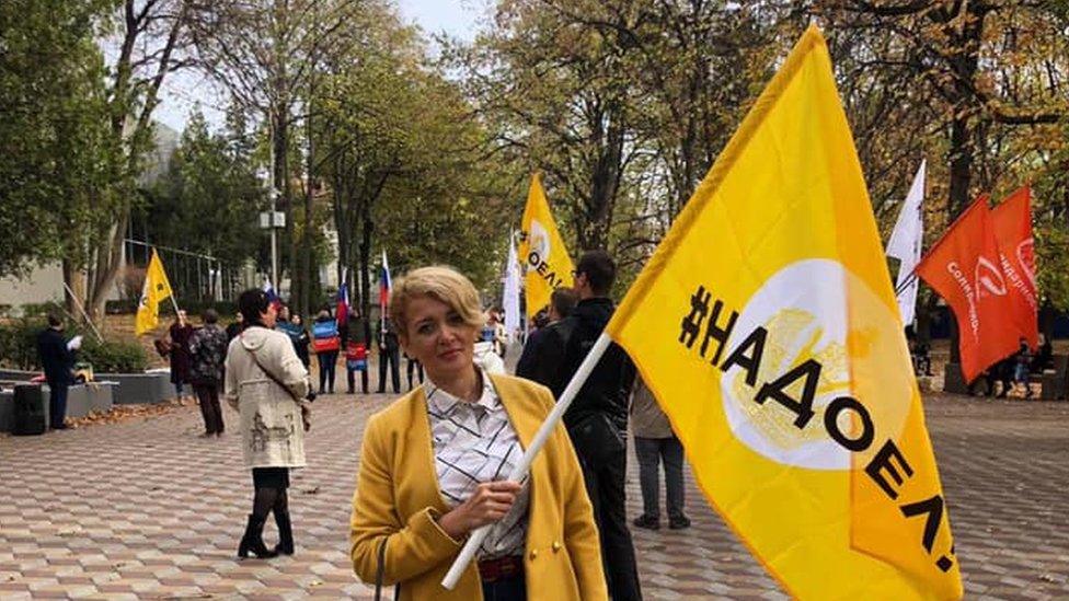 Anastasia Shevchenko holds a flag reading "Fed up"