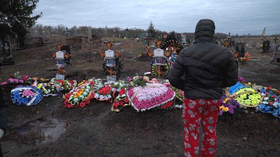 Dima looks at the graves of his mum, dad and grandparents