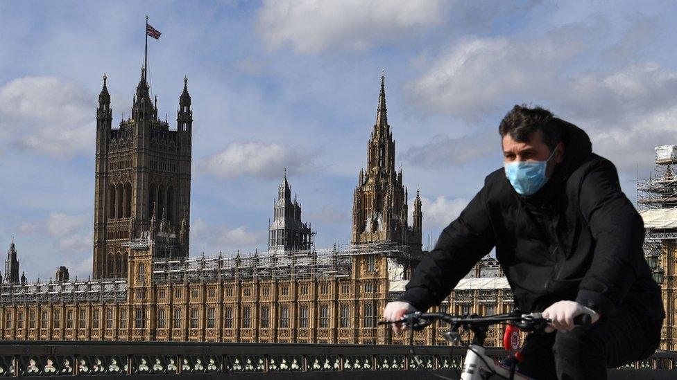 Man rides a bike outside the Houses of Parliament