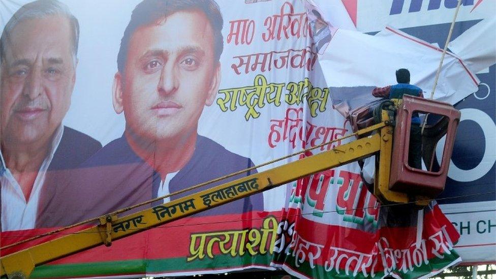 An Indian worker from the municipal corporation and Allahabad administration removes a banner poster of Uttar Pradesh chief minister, Akhilesh Yadav and his father Mulayam Singh Yadav at the roadside in Allahabad on January 4, 2016.