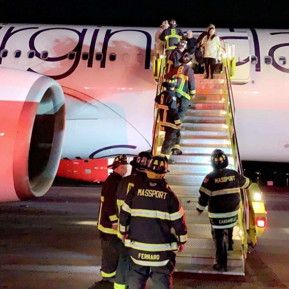 Firefighters board a Virgin Atlantic plane on the runway