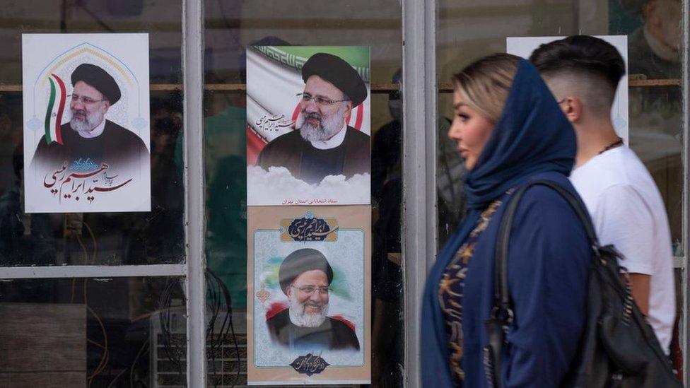 A couple walk past election posters for Ebrahim Raisi in southern Tehran, Iran (4 June 2021)