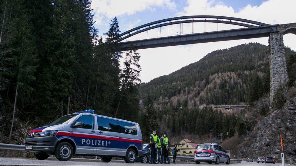 A police officer with protective gear at a roadblock stop car out of the Panznautal valley following the imposition of a quarantine due to the coronavirus on March 14, 2020 near Ischgl, Austria.