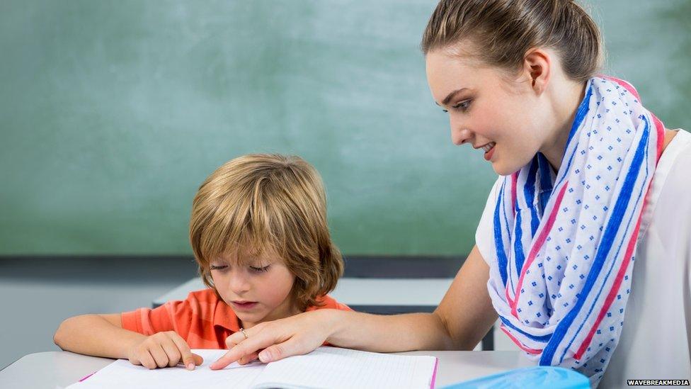 Child reading with teaching assistant