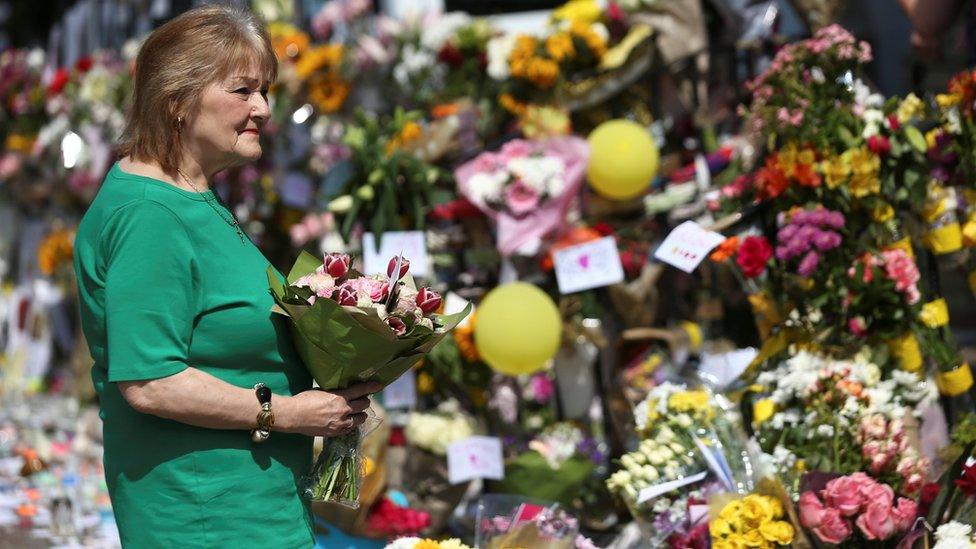 A woman carries flowers to leave with other tributes for the victims of the Grenfell fire