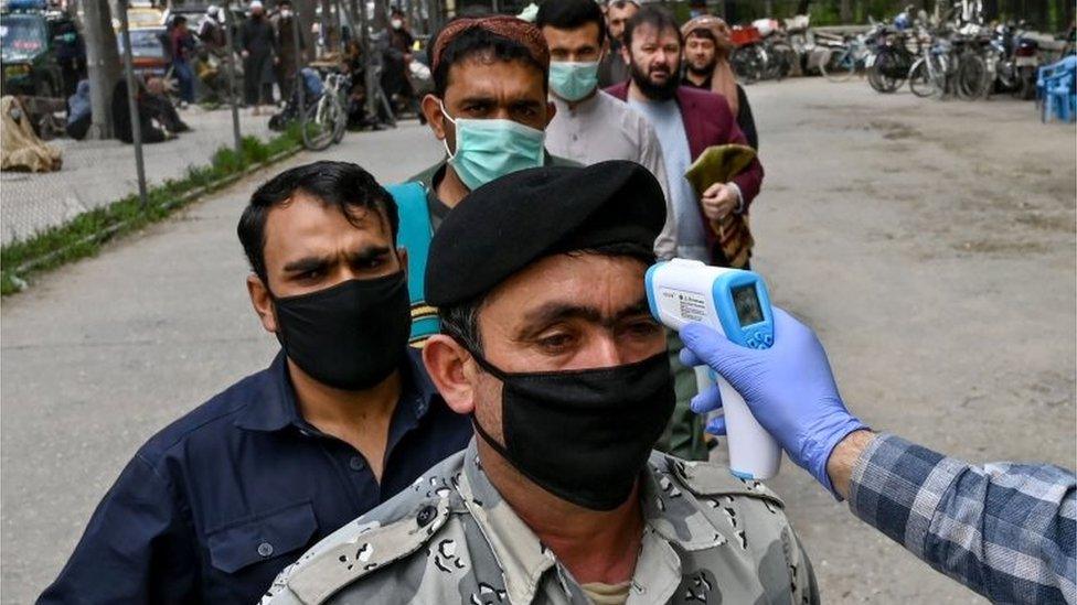 In this file photo taken on April 24, 2020 a health worker (R) checks the body temperature of a devotee as a preventive measure against the COVID-19 coronavirus before the Friday prayers on the first day of the Muslim holy month of Ramadan at Wazir Akbar Khan mosque in Kabul.