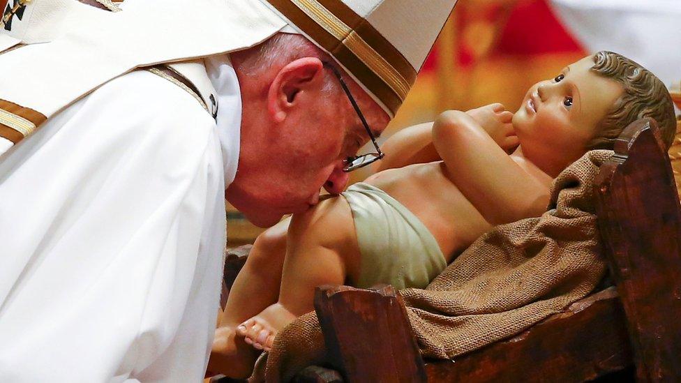 Pope Francis kisses a statue of baby Jesus at the end of the Christmas night Mass in Saint Peter's Basilica at the Vatican 24 December, 2016