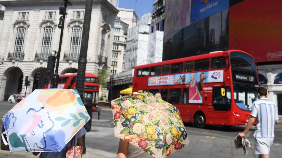 People use umbrellas to shelter from sun in London