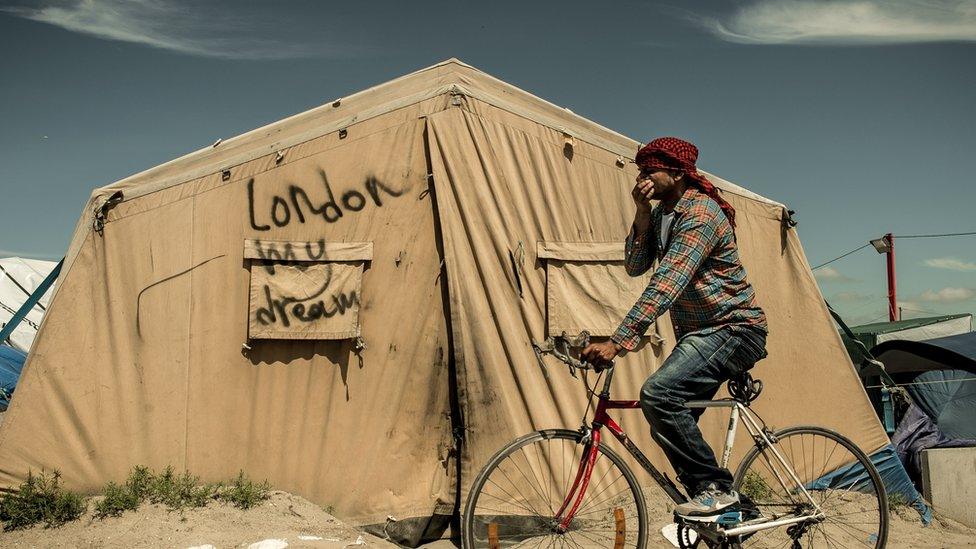 A man rides his bicycle at the Calais migrant camp