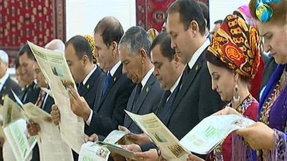 A Turkmen state TV shot of officials reading the poem