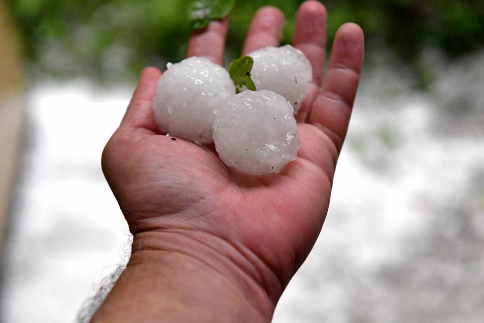 A man holds golf ball-size hail at Parliament House after a severe hail storm hit Canberra