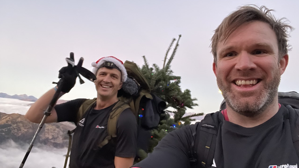 Ed Jackson and Ross Stirling on their climb. They are both smiling. Ed is wearing a Santa hat.