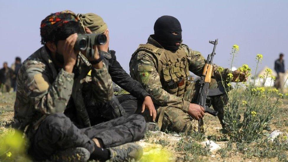 A member of the Kurdish-led Syrian Democratic Forces (SDF) looks through binoculars as he escorts a convoy carrying men, identified as Islamic State group fighters who surrendered, being transported out of IS's last holdout of Baghouz in Syria's northern Deir Ezzor province, on 20 February 2019.