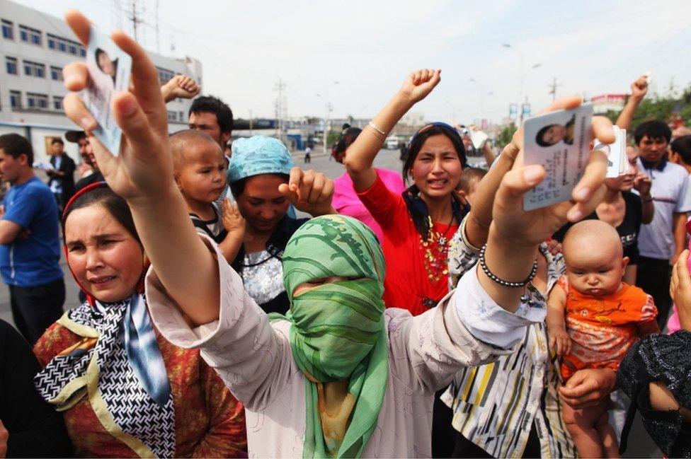 An Uighur woman holds the IDs of her relatives who are currently detained, as she and others protest on a street in July, 2009