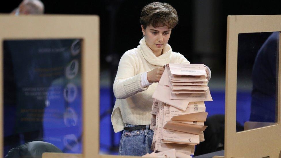 A woman sorts through peach ballot papers