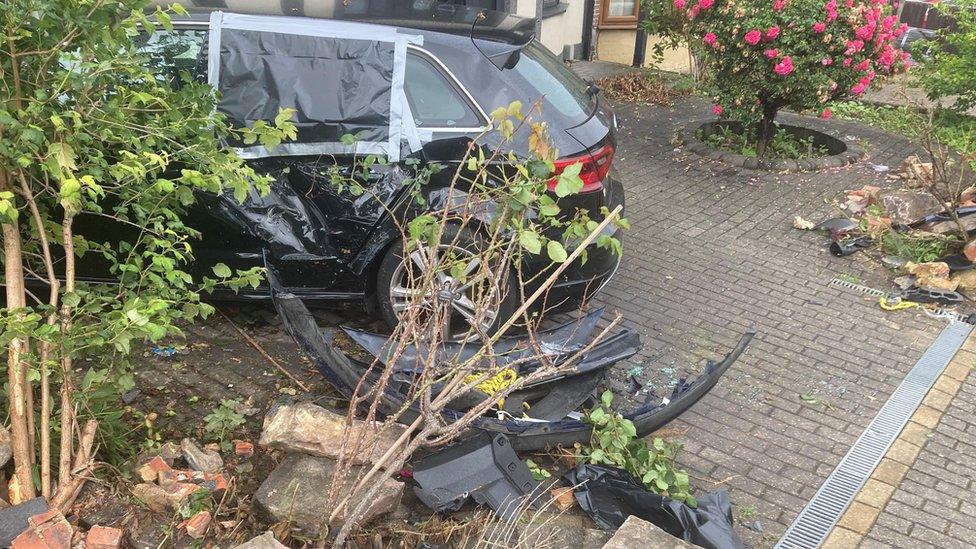 A car and a wall on a drive that has been damaged