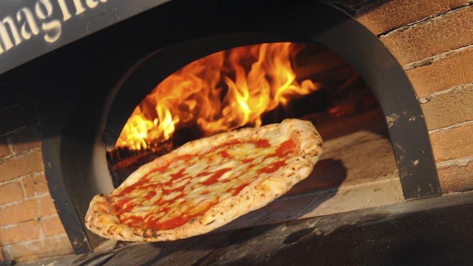 Pizza being taken out of a stove