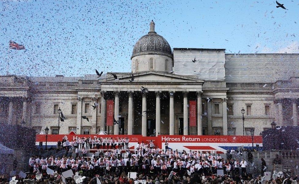 Confetti is released as spectators watch on as Athletes assemble