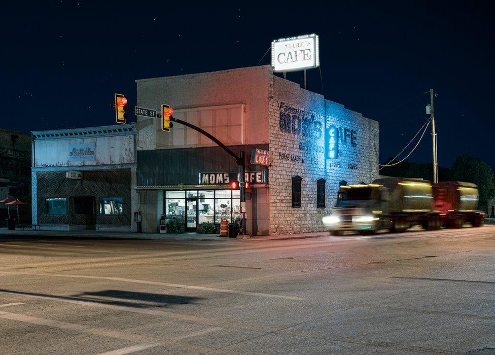 A night view of a closed cafe with a lorry passing