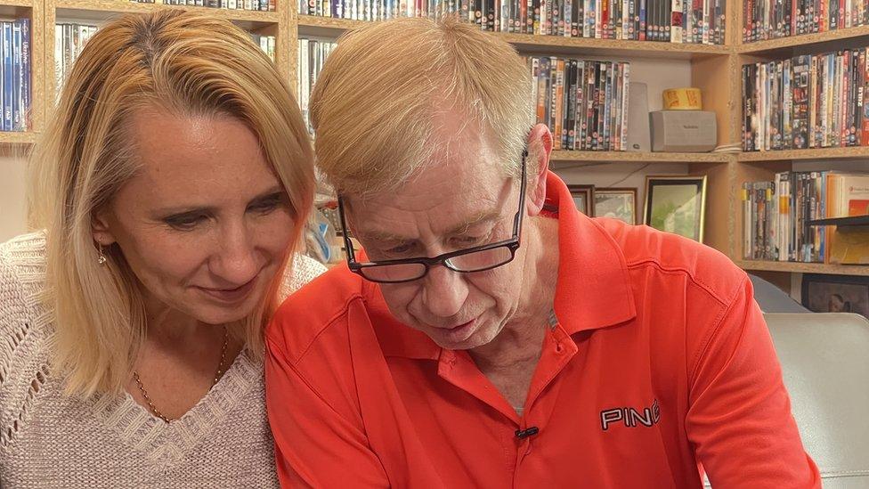 Robert Chesnaye with his wife Kateryna Rybalochka looking at a phone