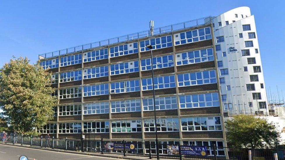 Google StreetView image of the school, a tall and wide building with many windows.