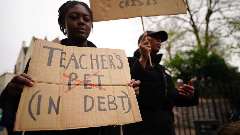 A teacher holding a placard on a picket line