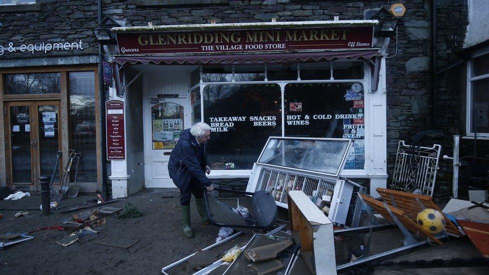 A shopkeeper in Glenridding assesses the damage following the latest flood