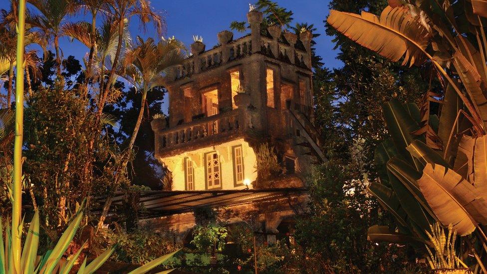 A section of the castle lit up at night, surrounded by fertile trees and gardens