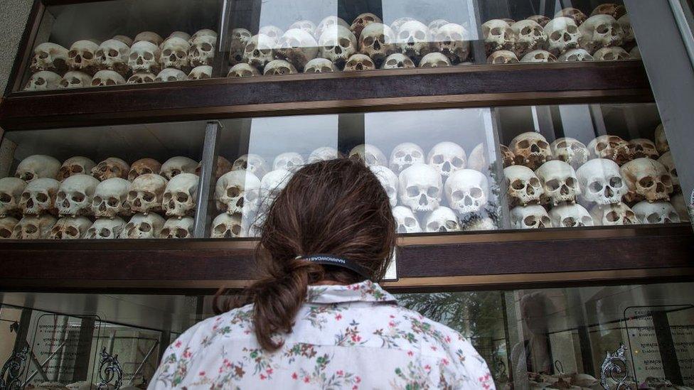 A young Cambodian woman looks at the main stupa in Choeung Ek Killing Fields in 2014