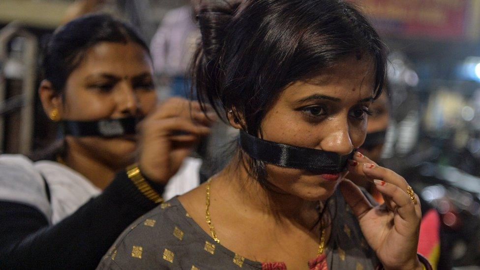 Supporters of Bharatiya Janata Party (BJP) cover their mouths with black fabric as they participate in a candle-lit procession calling for justice following the recent rape and murder of a 27-year-old veterinarian