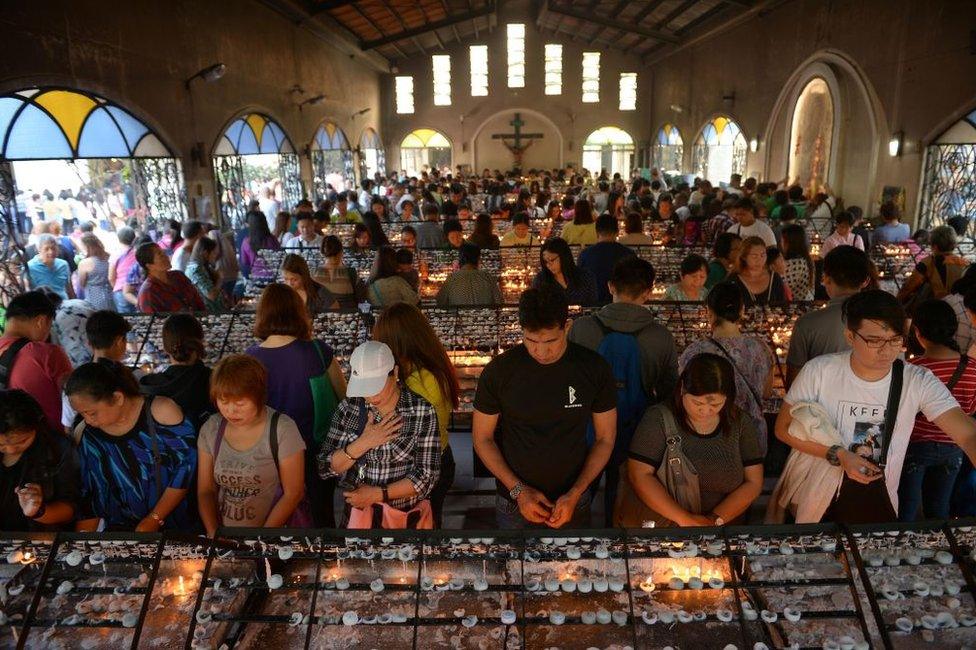 Catholic faithfuls light candles as they offer prayers during the observance of Ash Wednesday at a church in Manila on 1 March 2017