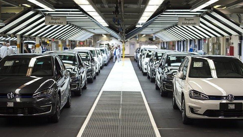 Employees of German car maker Volkswagen check cars at a assembly line of the VW plant in Wolfsburg