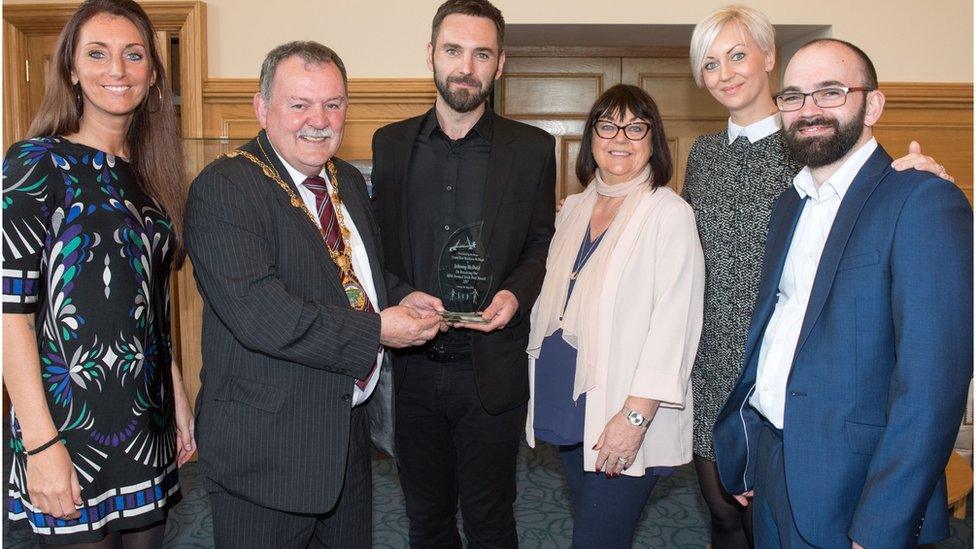 Johnny McDaid receiving his award from Mayor of Derry Maolíosa McHugh. Also pictured is the musician's mother Pauline, sisters Aine and Síle and brother Rory