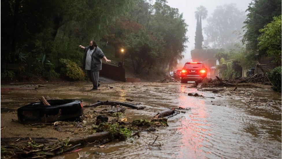 A resident attempts to help a vehicle stuck in a mudslide during the storm on Tuesday