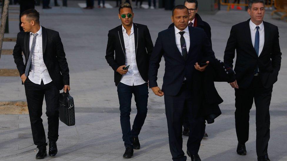 Neymar and his father arriving at court flanked by other men in suits